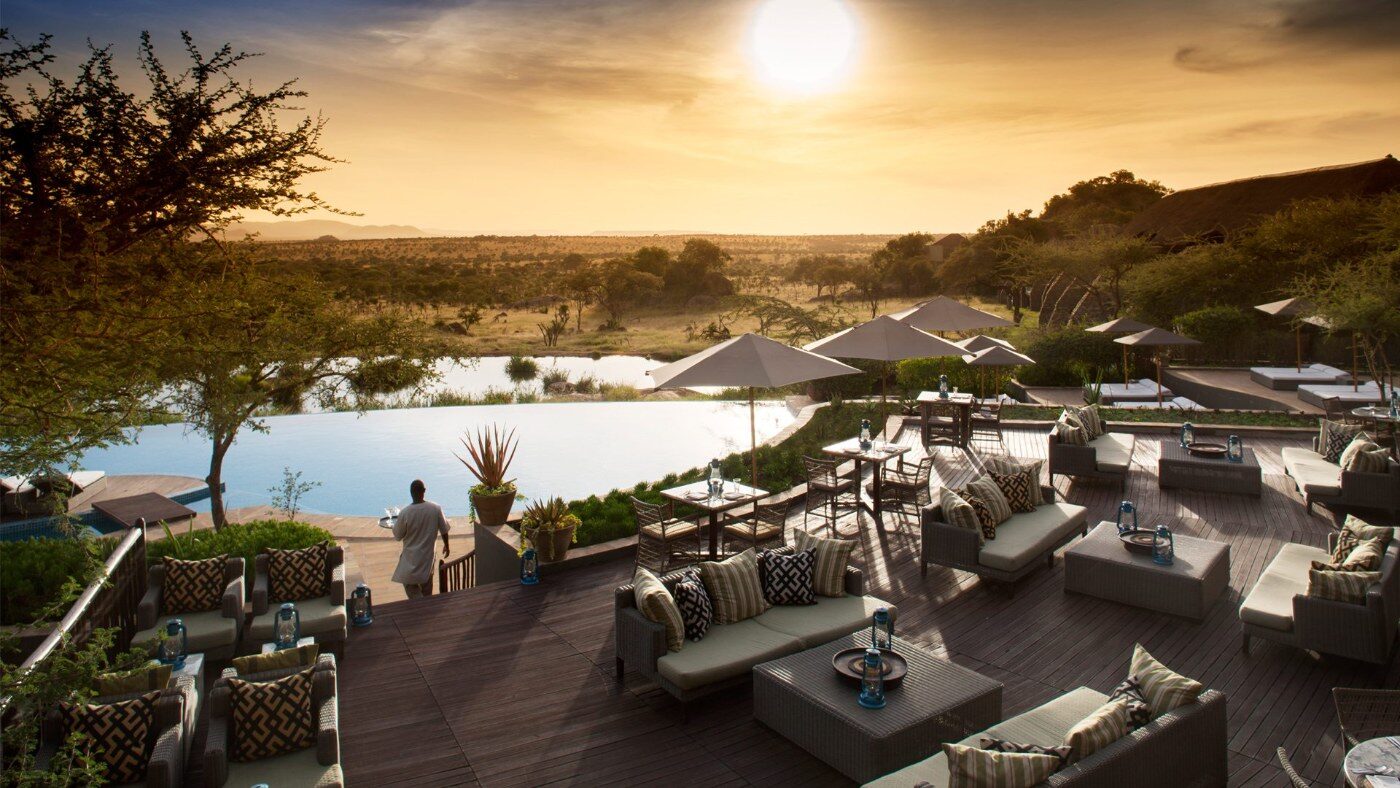 A lodge pool deck looking out over the bush at sunset