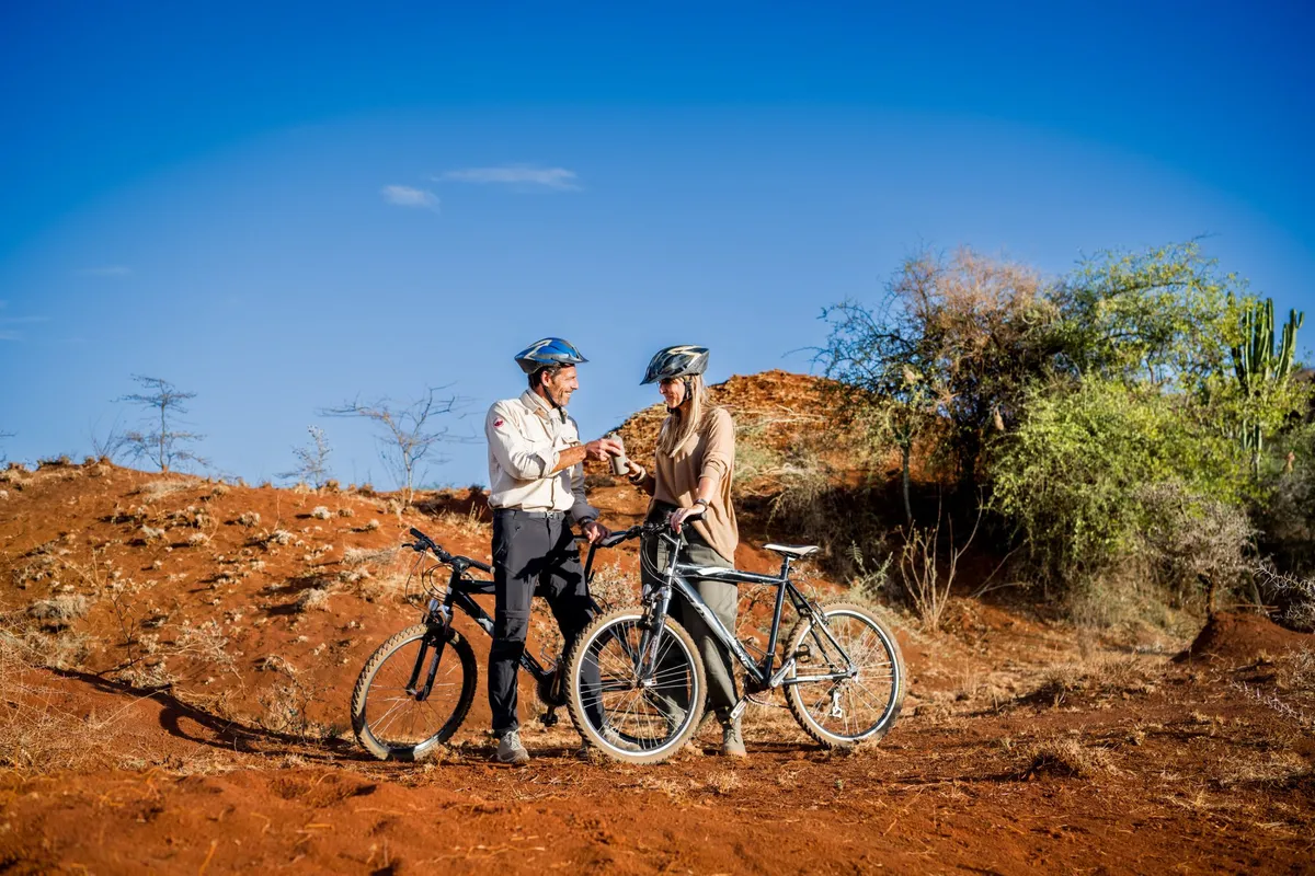 Two riders with mountain bikes on a red earth trail near Bashay Rift Lodge