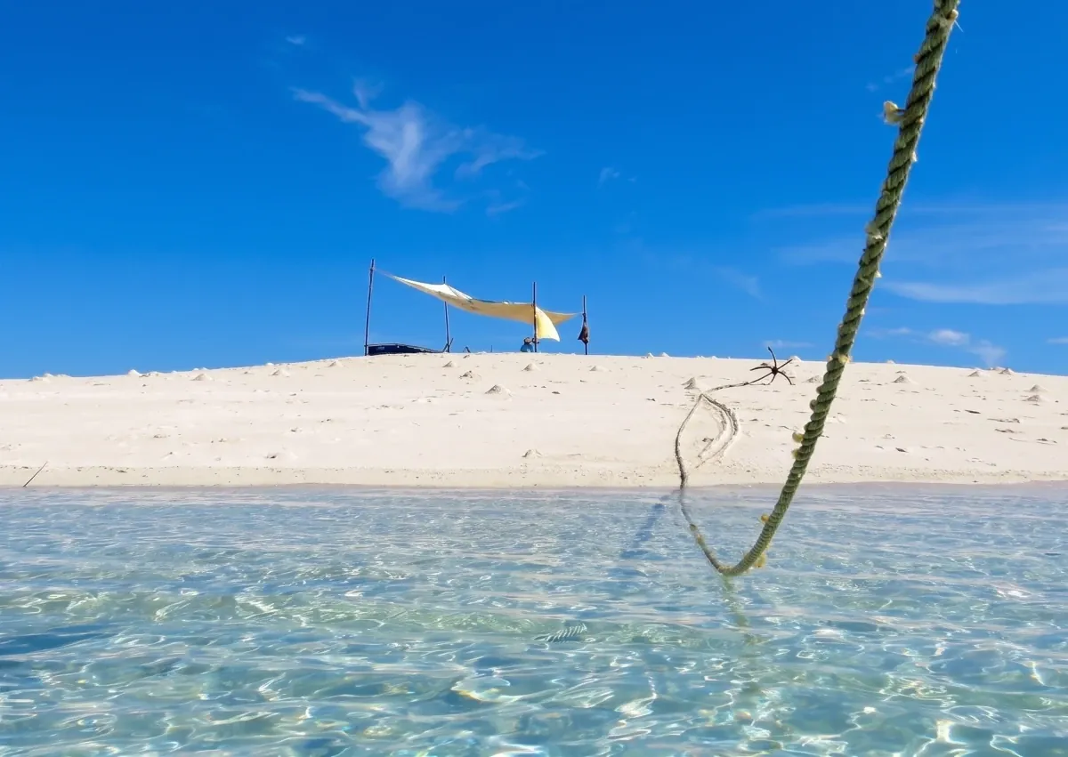 Mange sandbank with a shade shelter above clear shallow water