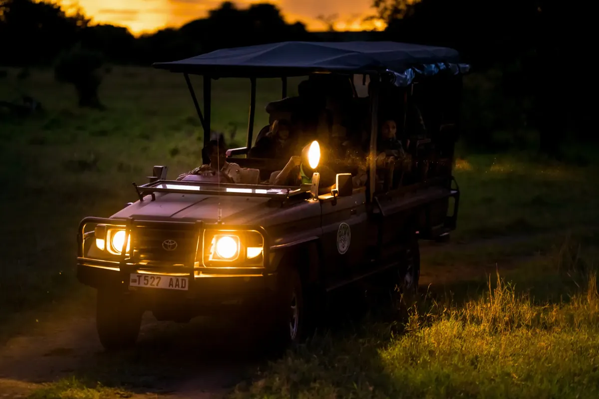 Ikoma Hills safari vehicle with headlights on at dusk for a night drive