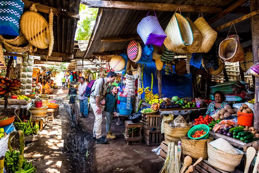 Guests walking between baskets and fruit stalls at a covered local market
