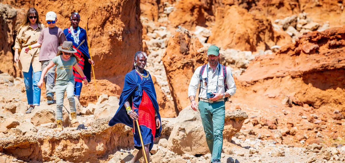 Guests walking with Maasai guides through the red rock of Olduvai Gorge